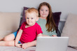 © ribalka yuli - Two children a boy and a girl lie on a sofa in home clothes and watch videos on a laptop and look at camera for a moment.