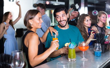 Wall Mural - adult vigorous male with female are talking and drinking cocktails on the party