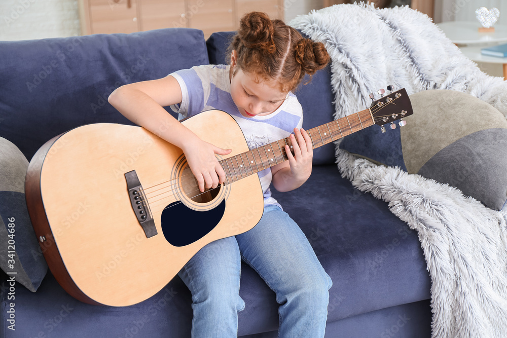 Cute little girl playing guitar at home