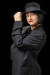 © 4th Life Photography - Smiling woman posing in man's jacket with a black hat (portrait isolated on black background)