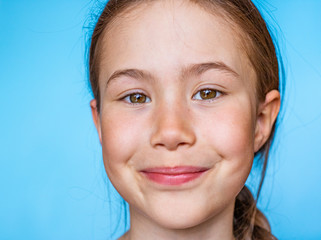 Portrait of a beautiful smiling girl with freckles looking at the camera. Banner template on blue background with copy space.