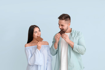 Sticker - Beautiful young couple with tasty chocolate on light background