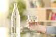 © PheelingsMedia - Woman hands holding a glass of bottled water at home