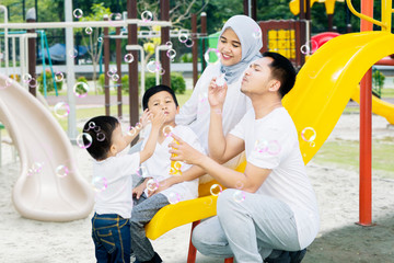 Wall Mural - Muslim family playing with bubble soap together