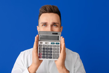 Canvas Print - Young man with calculator on color background