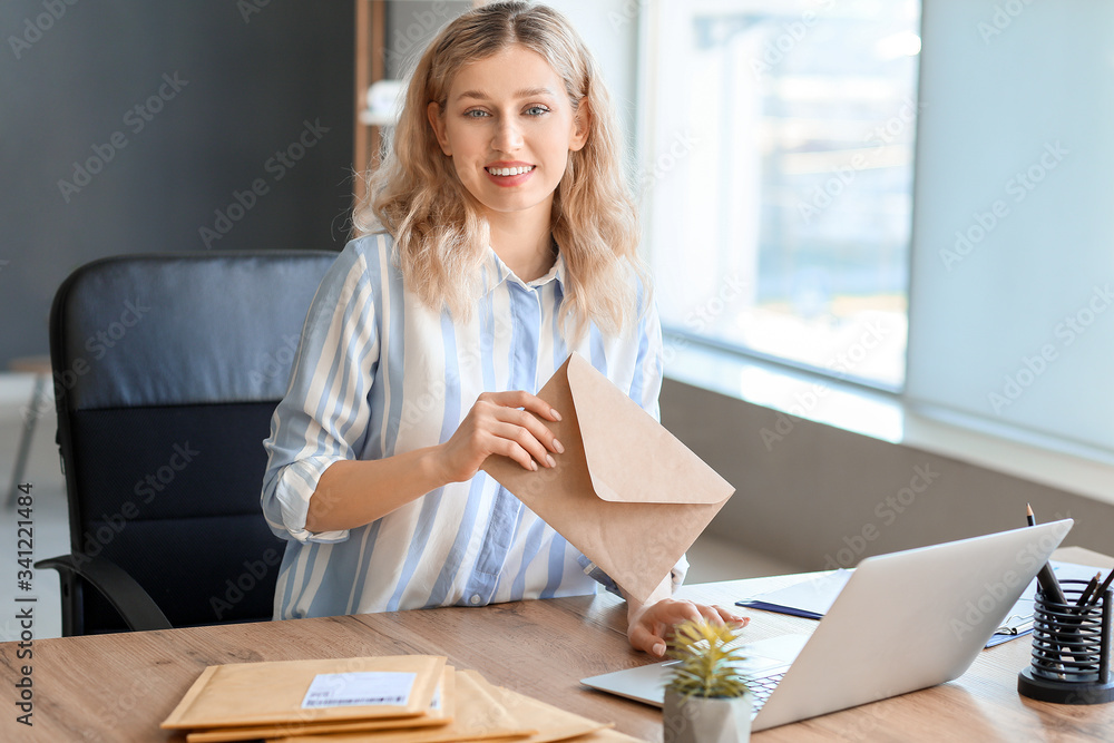 Young woman with laptop and letters in office
