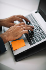 Close up of hands of businessman working on lap top.