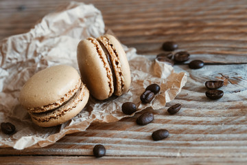 Deux macarons au café et grains de café sur une table en bois