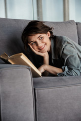 Sticker - Image of brunette cute pleased woman reading book and smiling