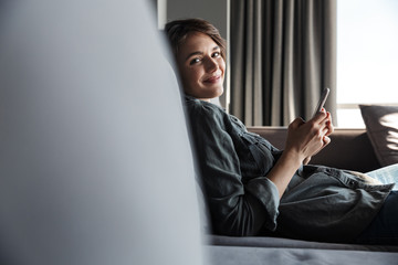 Canvas Print - Image of nice young happy woman using mobile phone and smiling