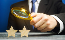 A Critic Holds A Magnifying Glass Over Two Stars. Rating, Feedback And Review Of A Restaurant Or Hotel. Quality Of Service. Evaluation Of Visitors