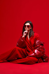 Wall Mural - Fashion model in red suit, down jacket and sunglasses.