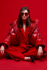 Wall Mural - Fashion model in red suit, down jacket and sunglasses.