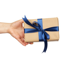 hand hold a wrapped gift in brown craft paper with tied silk blue bows, subject is isolated on a white background