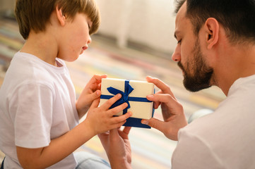 Close-up child. Son and father opening present.