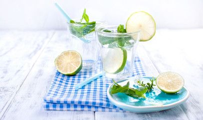 Two glasses of water with citruses and mint on a white background. Summer refreshing drink. Copy space