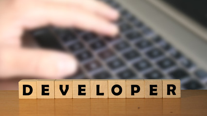 developer message word on a wooden desk on cube blocks with a green nature background.