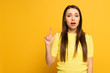 Existed girl pointing with finger and looking at camera on yellow background