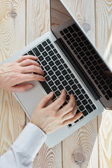 Poster - Top view of man's hands typing on laptop in sunny day. Coworking or working at home concept image.