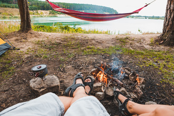 Wall Mural - couple sitting near camp fire with beautiful view of lake
