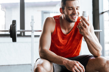 happy sportsman looking at bottle with probiotic lettering in gym
