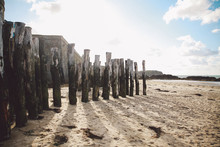 Wooden Posts On Sand At Beach Against Sky