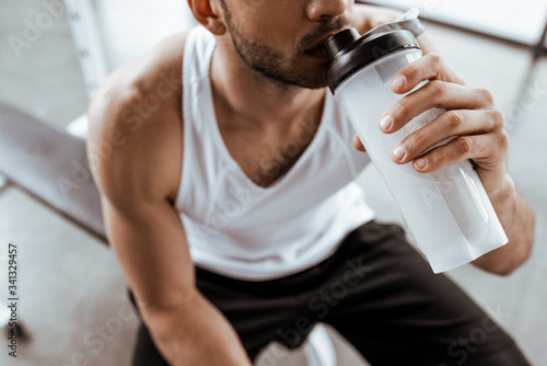 cropped view of sportsman drinking protein milkshake while holding sports bottle Tableau sur Toile