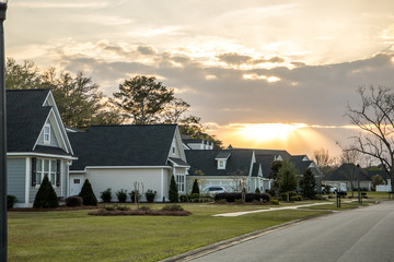 A street view of a new construction neighborhood with larger landscaped homes and houses with yards and sidewalks taken near sunset with copy space