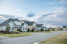 A Street View Of A New Construction Neighborhood With Larger Landscaped Homes And Houses With Yards And Sidewalks Taken Near Sunset With Copy Space