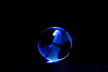 Close-up Of Crystal Ball With Illuminated Blue Lights Against Black Background