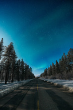 Road Amidst Trees Against Clear Sky At Night