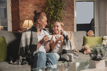 Tea drinking, talking. Mother and daughter during self-insulation at home while quarantined, family time cozy, comfort, domestic life. Cheerful, happy smiling models. Safety, prevention, love concept.