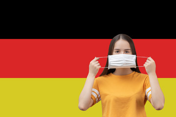 Wall Mural - Prevention of coronavirus in Germany. Young girl puts on an antibacterial medical mask on a flag background with copyspace