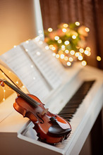 Musical Instruments: The Violin Lies On An Electronic Piano, The Background Is Bright Bokeh. Music Concept