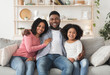 © Prostock-studio - Happy Black Family Of Three Posing At Home, Embracing And Smiling