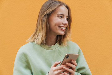 Poster - Portrait of pleased blonde woman smiling and using mobile phone