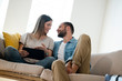 © Westend61 - Happy young couple relaxing on couch at home with tablet