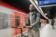 © Westend61 - Stylish man with a bicycle, headphones and smartphone in a metro station