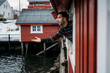 Tourist leaning out of window of a hut, Lofoten, Norway
