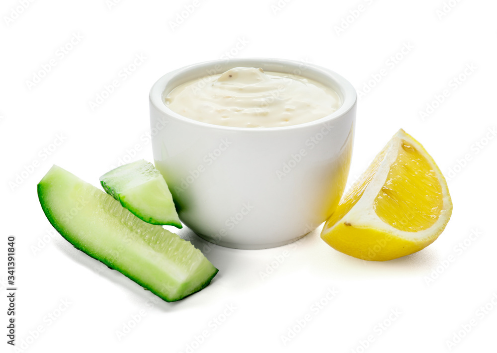 Delicious yogurt sauce with cucumber in bowl on white background