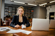 © Marat - Beautiful businesswoman sitting in the office and smiling looking out the window