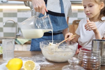 Children mix the flour in bowl, pour milk in dough