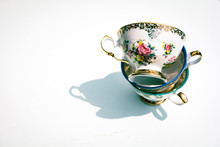 Stack Of Vintage Porcelain Tea Cups With Floral And Golden Decorations On White Background. Concept Of Afternoon Tea Party And Fine Bone China