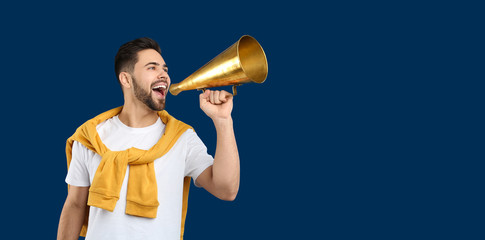 Wall Mural - Young man with megaphone on blue background