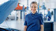 © Gorodenkoff - Beautiful Empowering Female Car Mechanic is in a Vehicle Service. She Looks Happy, Smiles and Looks at a Camera. Specialist is Wearing Safety Glasses.