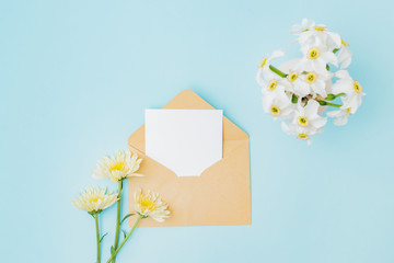 Wall Mural - mockup white greeting card and envelope with flowers in a vase on a blue background