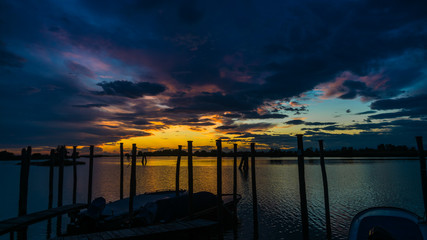 Wall Mural - colorful sunset with many clouds at a boat landing stage in Cavallino, Italy