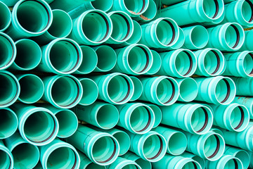 Large plastic pipes are stacked creating an abstract pattern while waiting to be installed under ground.