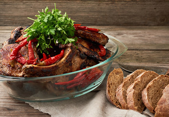 grilled pork steaks on the bone lie in a transparent glass plate on a wooden table