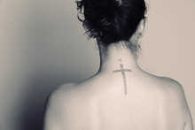 Rear View Of Shirtless Woman With Cross Tattoo On Back Over White Background